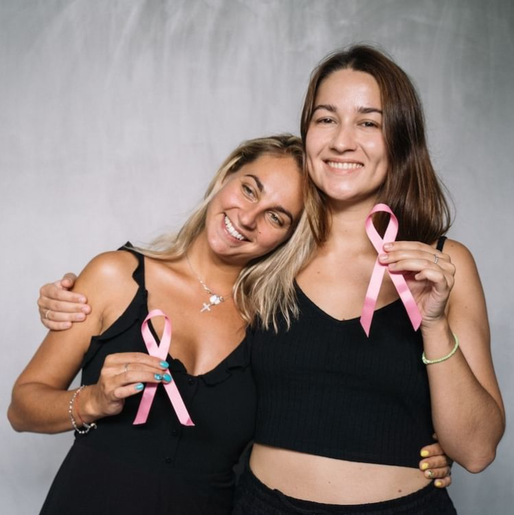 Two women holding pink ribbons in their hands.